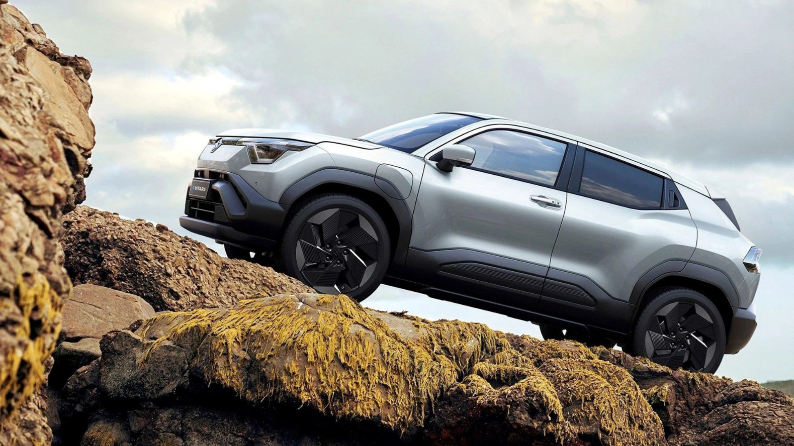 A silver Suzuki e Vitara driving up a rocky hill.